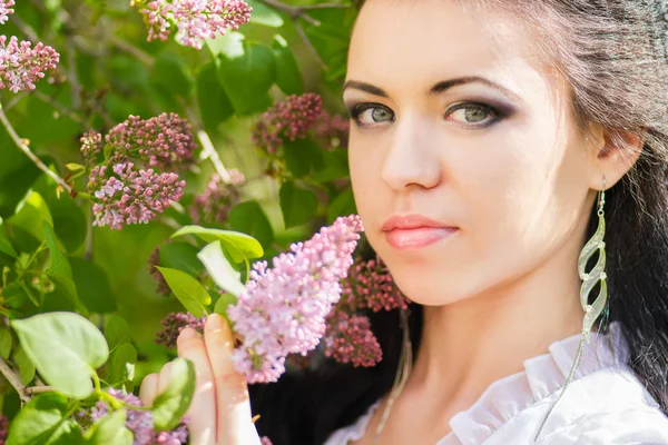 Bella giovane bruna in posa nella natura. Ragazza con capelli e trucco in abito romantico bianco — Foto Stock