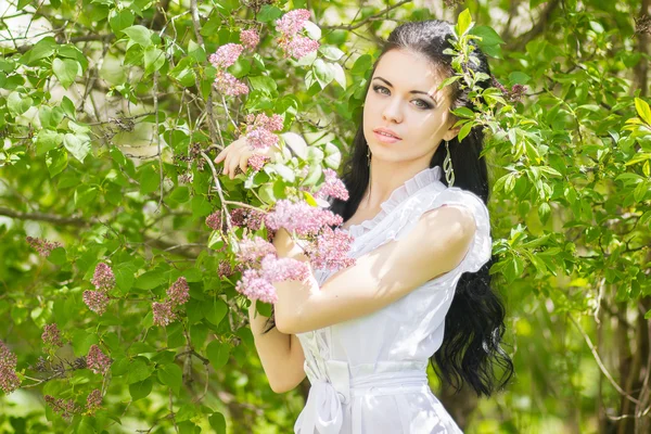 Mooie jonge brunette poseren in de natuur. meisje met haar en make-up in romantische witte jurk — Stockfoto