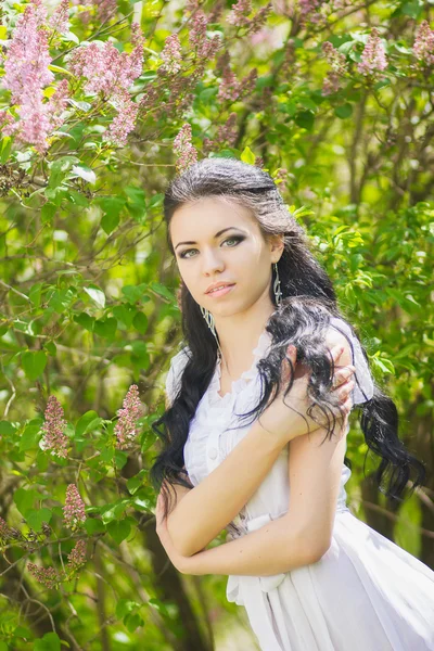Beautiful young brunette posing in nature. Girl with hair and makeup in white romantic dress Royalty Free Stock Photos