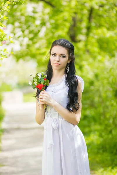 Mooie jonge brunette poseren in de natuur. meisje met haar en make-up in romantische witte jurk — Stockfoto