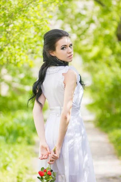 Frumos tineri bruneta pozând în natură. Fata cu păr și machiaj în rochie romantică albă — Fotografie, imagine de stoc