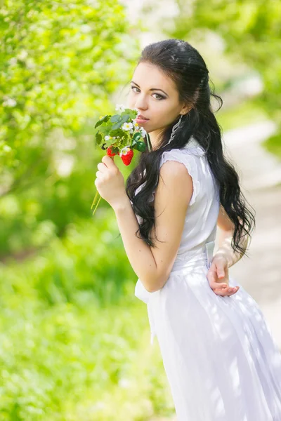 Linda jovem morena posando na natureza. Menina com cabelo e maquiagem em vestido romântico branco — Fotografia de Stock