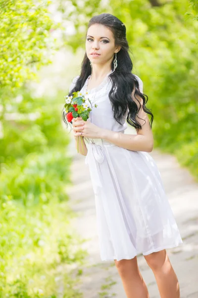 Bella giovane bruna in posa nella natura. Ragazza con capelli e trucco in abito romantico bianco — Foto Stock