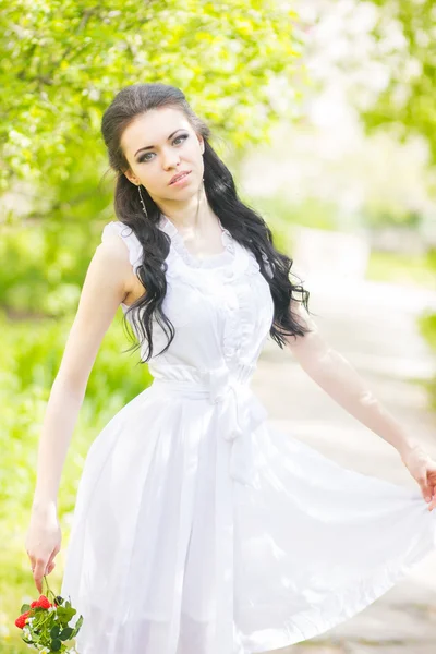 Hermosa joven morena posando en la naturaleza. Chica con pelo y maquillaje en vestido romántico blanco —  Fotos de Stock