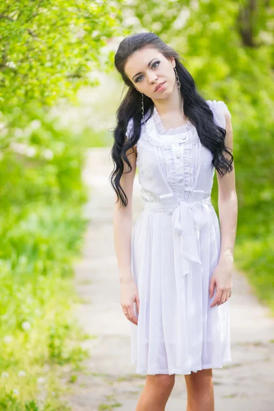 美しい若いブルネットの自然の中でポーズします。少女の髪と白いロマンチックなドレスを着て化粧 — ストック写真