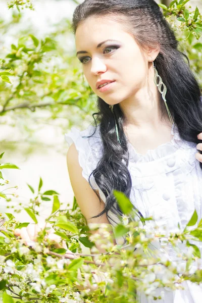 Hermosa joven morena posando en la naturaleza. Chica con pelo y maquillaje en vestido romántico blanco —  Fotos de Stock