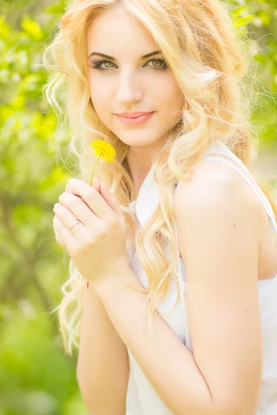 Porträtt av en vacker ung blond kvinna med maskrosor. flicka poserar i naturen och ler — Stockfoto