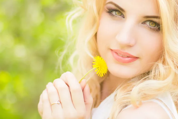 Retrato de una hermosa joven rubia con dientes de león. Chica posando en la naturaleza y sonriendo —  Fotos de Stock