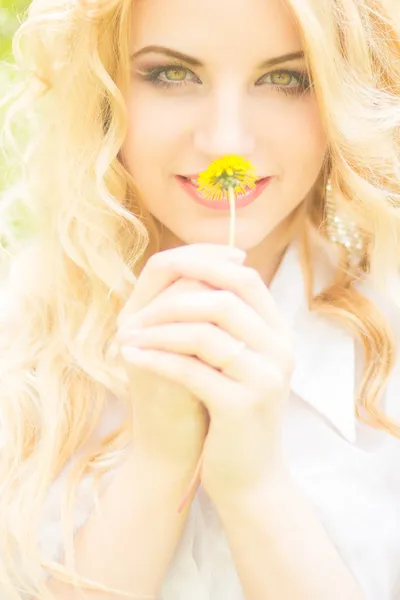 Portrait of a beautiful young blonde woman with dandelions. Girl posing in nature and smiling — Stock Photo, Image