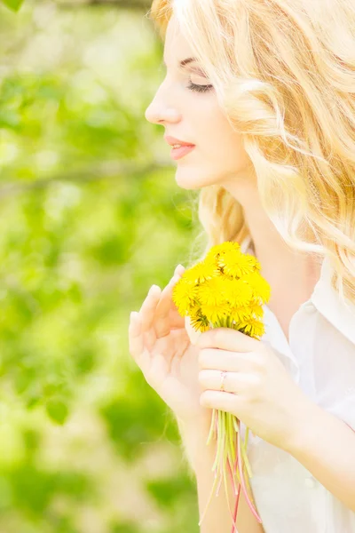 Portrait d'une belle jeune femme blonde avec des pissenlits. Fille posant dans la nature et souriant — Photo