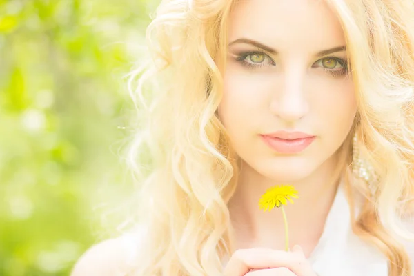 Porträt einer schönen jungen blonden Frau mit Löwenzahn. Mädchen posiert in der Natur und lächelt — Stockfoto