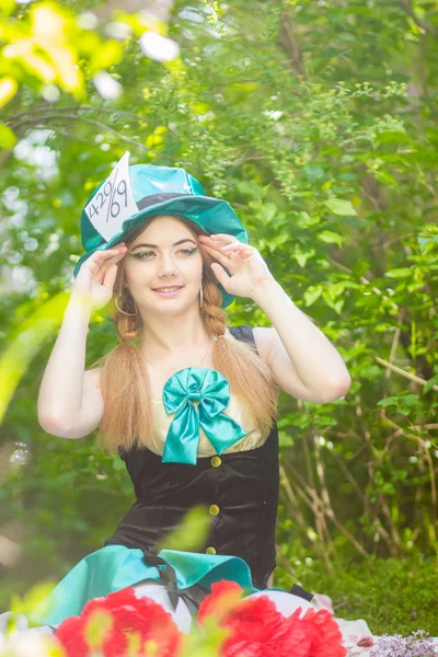 Ritratto di una bella giovane donna in costume del Cappellaio Pazzo in natura. Ragazza in posa con un mazzo di peonie rosse — Foto Stock