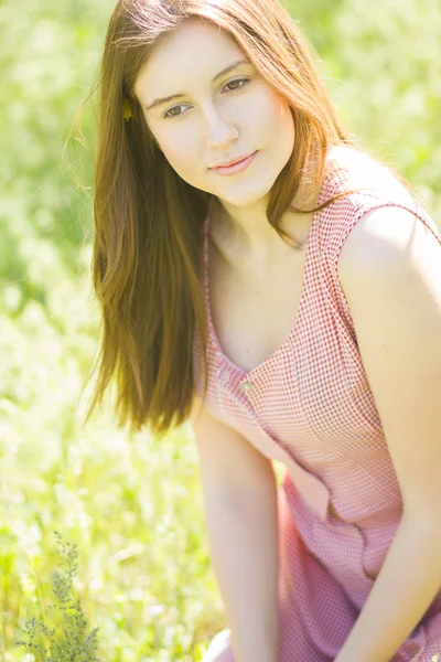 Portrait of a beautiful young woman with brown hair in retro plaid dress. Girl posing in nature with a small bouquet of violets — Stock Photo, Image