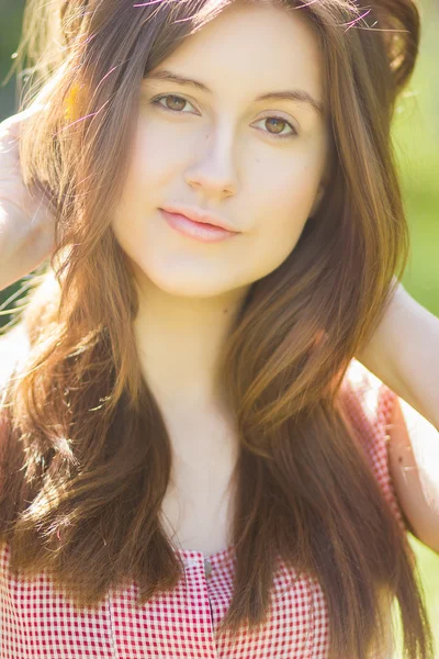 Retrato de una hermosa mujer joven con cabello castaño en vestido retro a cuadros. Chica posando en la naturaleza con un pequeño ramo de violetas —  Fotos de Stock