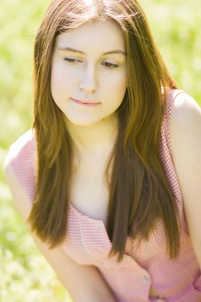 Retrato de una hermosa mujer joven con cabello castaño en vestido retro a cuadros. Chica posando en la naturaleza con un pequeño ramo de violetas —  Fotos de Stock