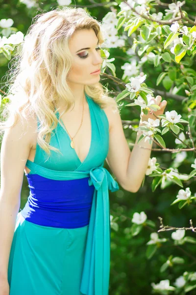 Ritratto di una bella giovane donna bionda con i capelli lunghi in un abito lungo blu con una fessura alta in natura . — Foto Stock