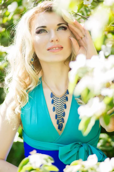 美丽年轻的金发女郎与长长的头发在长长的蓝色的连衣裙在自然高衩的肖像. — 图库照片