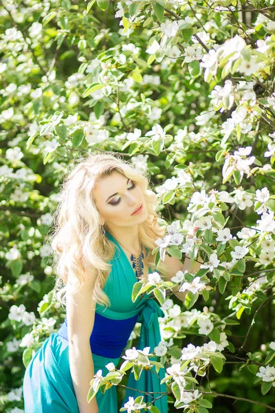 Retrato de uma bela jovem loira com cabelos longos em um longo vestido azul com uma alta fenda na natureza . — Fotografia de Stock