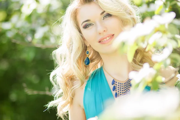 Retrato de uma bela jovem loira com cabelos longos em um longo vestido azul com uma alta fenda na natureza . — Fotografia de Stock