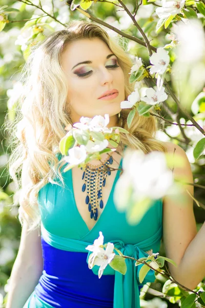 Porträt einer schönen jungen blonden Frau mit langen Haaren in einem langen blauen Kleid mit hohem Schlitz in der Natur. — Stockfoto