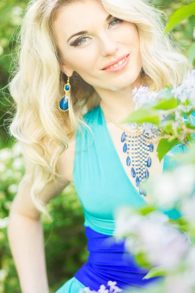 Retrato de uma bela jovem loira com cabelos longos em um longo vestido azul com uma alta fenda na natureza . — Fotografia de Stock