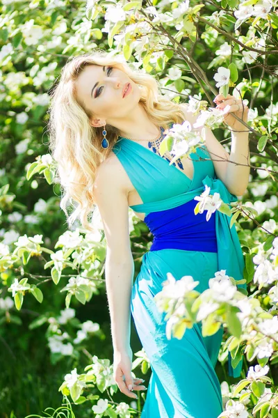 Retrato de una hermosa mujer rubia joven con el pelo largo en un vestido azul largo con una hendidura alta en la naturaleza . —  Fotos de Stock