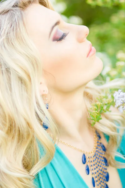 Retrato de una hermosa mujer rubia joven con el pelo largo en un vestido azul largo con una hendidura alta en la naturaleza . —  Fotos de Stock