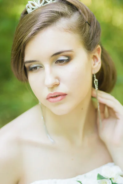 Portrait of a beautiful young bride in nature. Young woman holding a small bouquet of white roses in their hands — Stock Photo, Image