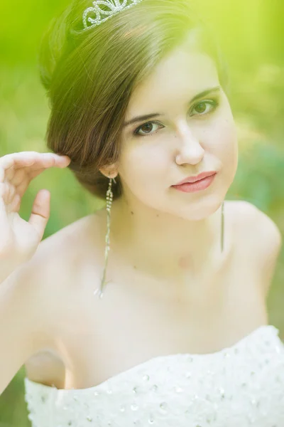 Retrato de uma bela noiva jovem na natureza. Jovem segurando um pequeno buquê de rosas brancas em suas mãos — Fotografia de Stock