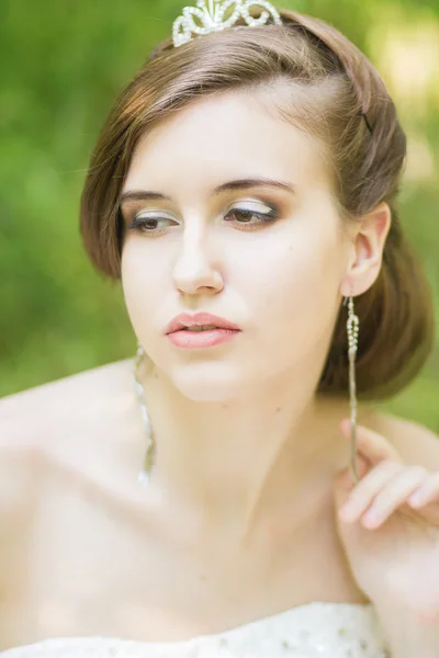 Portrait of a beautiful young bride in nature. Young woman holding a small bouquet of white roses in their hands — Stock Photo, Image