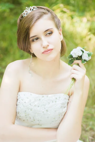 Portrét krásné mladé nevěsty v přírodě. mladá žena drží malou kytici bílých růží v ruce — Stock fotografie