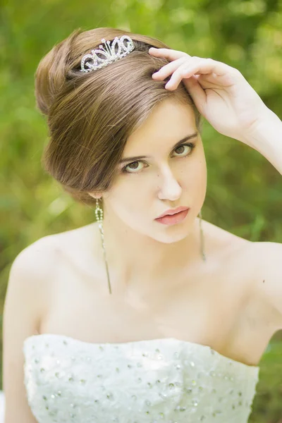 Porträt einer schönen jungen Braut in der Natur. junge Frau mit einem kleinen Strauß weißer Rosen in der Hand — Stockfoto