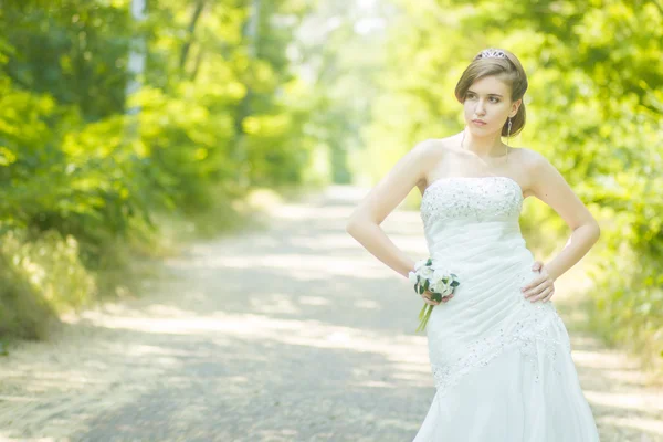 Porträt einer schönen jungen Braut in der Natur. junge Frau mit einem kleinen Strauß weißer Rosen in der Hand — Stockfoto