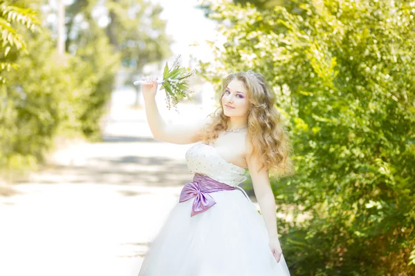 Retrato de uma bela noiva jovem na natureza em um vestido de casamento magnífico . — Fotografia de Stock