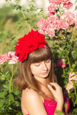 kırmızı ışık elbise kahverengi saçlı güzel bir genç kadının portresi. Bahçedeki gül çalılar ile kız