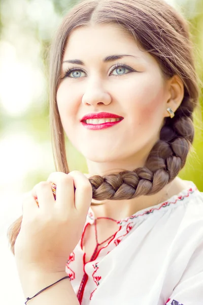 Moda ao ar livre retrato de mulher de cabelo marrom em traje nacional ucraniano bordado. Mulher bonita com maquiagem brilhante posando na natureza — Fotografia de Stock