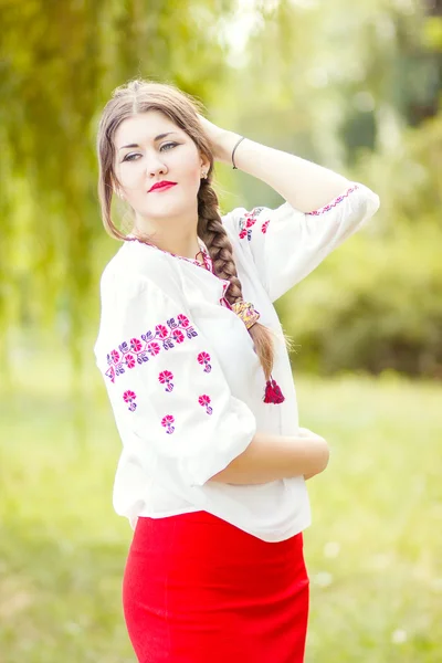 Outdoor fashion brown hair woman portrait in embroidered Ukrainian national costume. Beautiful woman with bright makeup posing on the nature — Stock Photo, Image