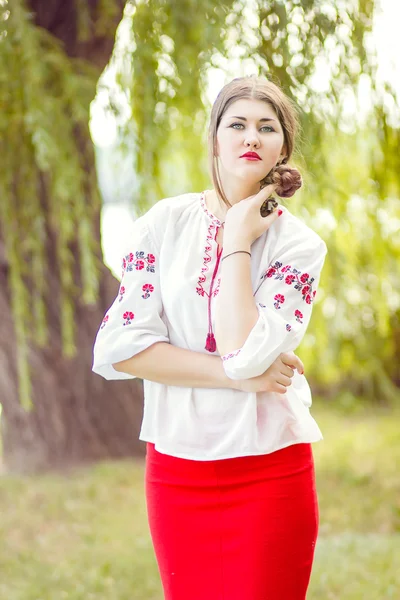 Outdoor fashion brown hair woman portrait in embroidered Ukrainian national costume. Beautiful woman with bright makeup posing on the nature — Stock Photo, Image