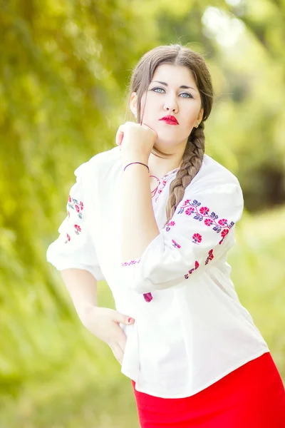 Outdoor fashion brown hair woman portrait in embroidered Ukrainian national costume. Beautiful woman with bright makeup posing on the nature — Stock Photo, Image