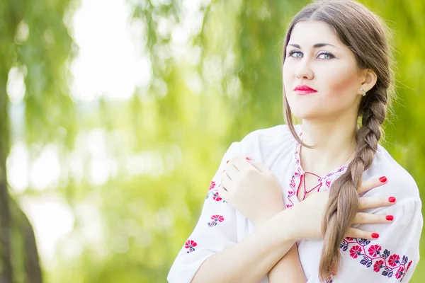 Mode extérieure cheveux bruns portrait de femme en costume national ukrainien brodé. Belle femme avec un maquillage lumineux posant sur la nature — Photo