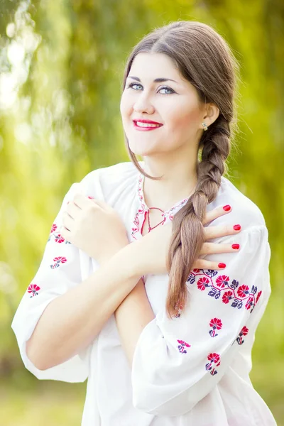 Moda ao ar livre retrato de mulher de cabelo marrom em traje nacional ucraniano bordado. Mulher bonita com maquiagem brilhante posando na natureza — Fotografia de Stock
