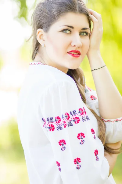 Retrato de mujer de pelo castaño de moda al aire libre en traje nacional ucraniano bordado. Hermosa mujer con maquillaje brillante posando sobre la naturaleza — Foto de Stock