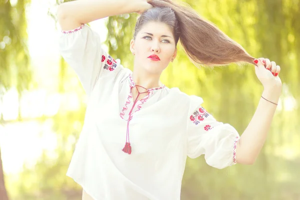 Retrato de mujer de pelo castaño de moda al aire libre en traje nacional ucraniano bordado. Hermosa mujer con maquillaje brillante posando sobre la naturaleza — Foto de Stock