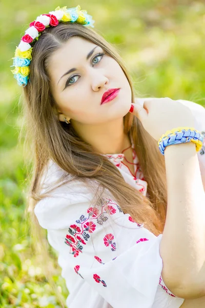 Outdoor portrait young woman with long brown hair. The girl floral accessories, she poses lying on the grass in the park — Stock Photo, Image