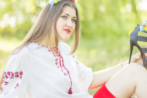 Outdoor portrait young woman with long brown hair. The girl floral accessories, she poses lying on the grass in the park — Stock Photo, Image