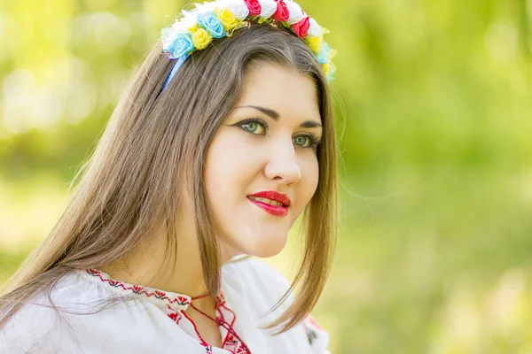 Outdoor portrait young woman with long brown hair. The girl floral accessories, she poses lying on the grass in the park — Stock Photo, Image