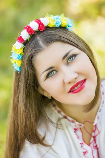 Retrato al aire libre mujer joven con el pelo castaño largo. Los accesorios florales de la muchacha, ella posa tendida en la hierba en el parque —  Fotos de Stock