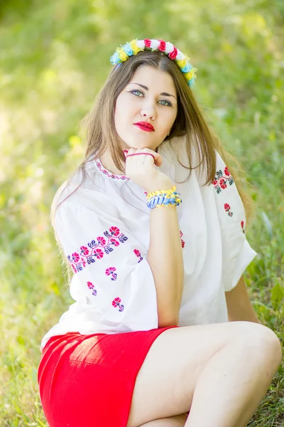 Portrait extérieur jeune femme aux longs cheveux bruns. La fille accessoires floraux, elle pose couchée sur l'herbe dans le parc — Photo