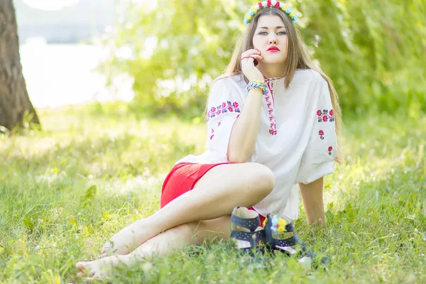 Outdoor portrait young woman with long brown hair. The girl floral accessories, she poses lying on the grass in the park — Stock Photo, Image