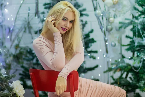 Charmante Blonde Vrouw Beige Sexy Jurk Zittend Rode Stoel Achtergrond — Stockfoto